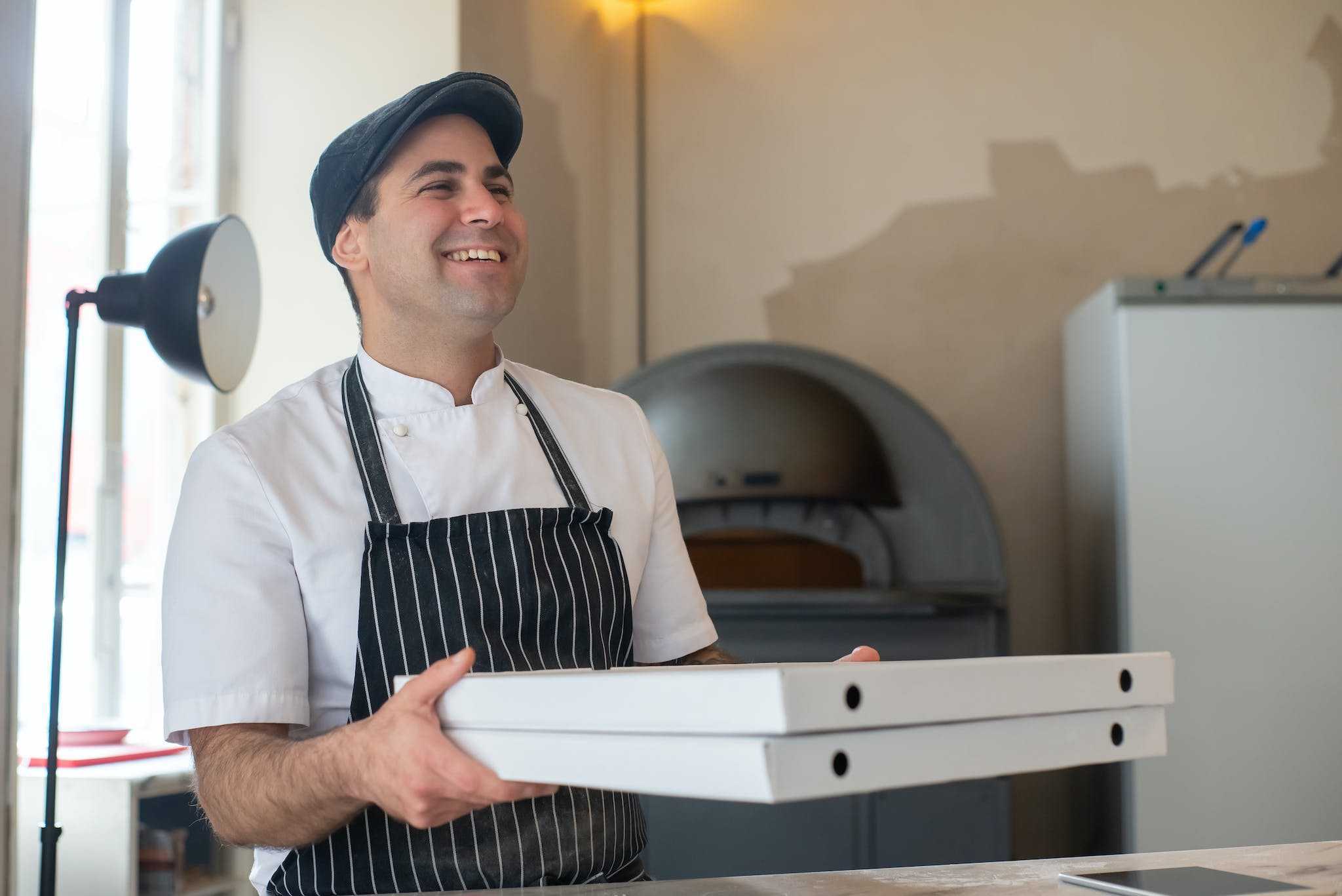 a chef carrying pizza